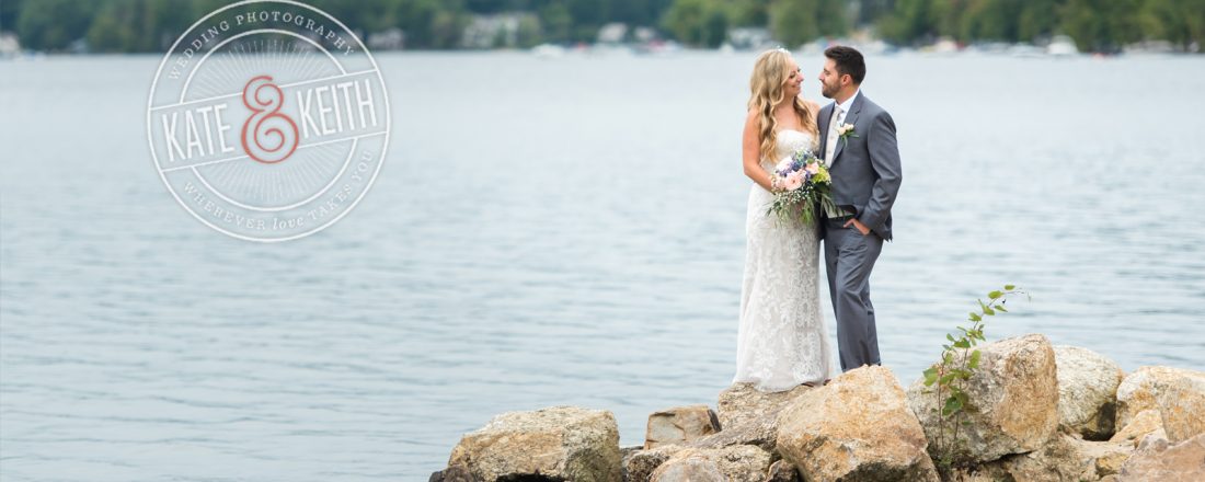 Bride and groom on rocks on shores of Lake Winnipesaukee, New Hampshire